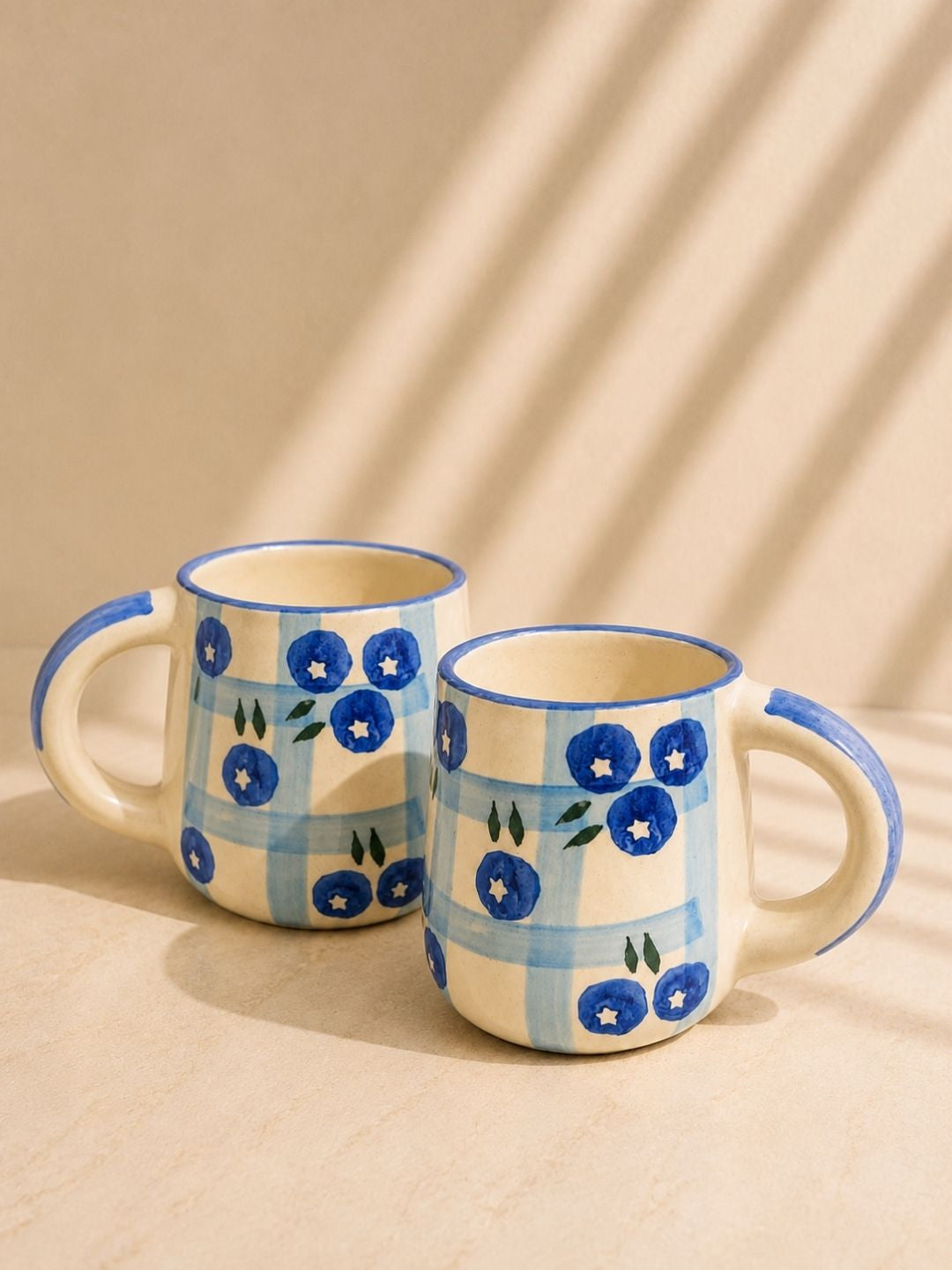 Artisan-made ceramic tea mug featuring blueberry illustrations and blue checkered pattern.