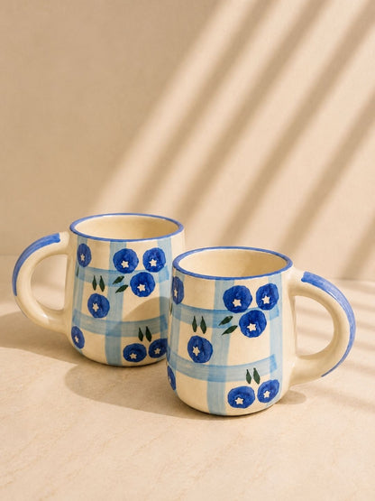 Artisan-made ceramic tea mug featuring blueberry illustrations and blue checkered pattern.